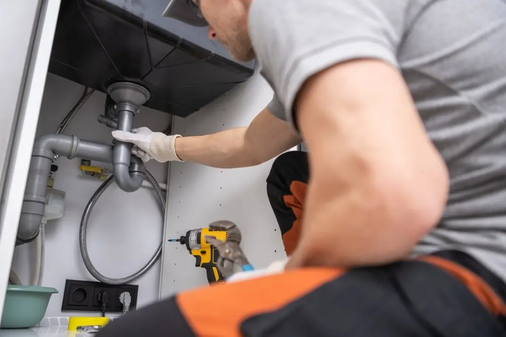 Plumber repairing pipework under a kitchen sink